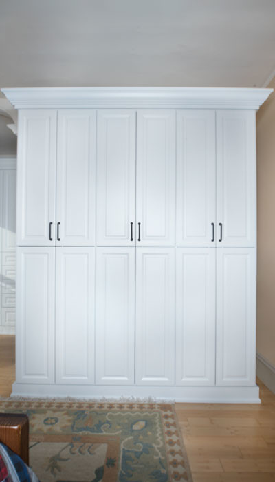 Imagen de armario unisex tradicional de tamaño medio con armarios con paneles con relieve, puertas de armario blancas y suelo de madera clara