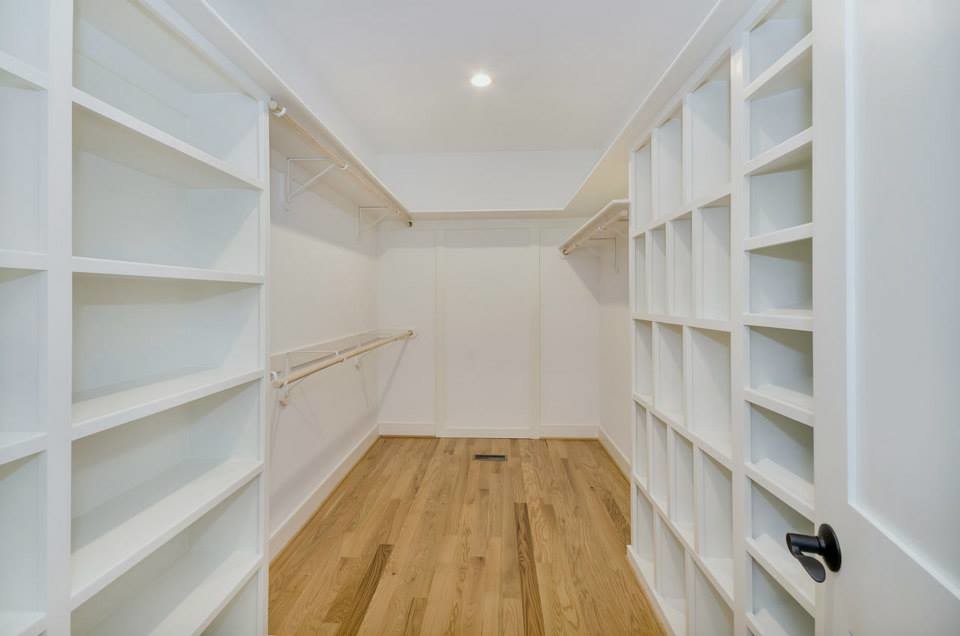 Imagen de armario y vestidor campestre con puertas de armario blancas y suelo de madera en tonos medios