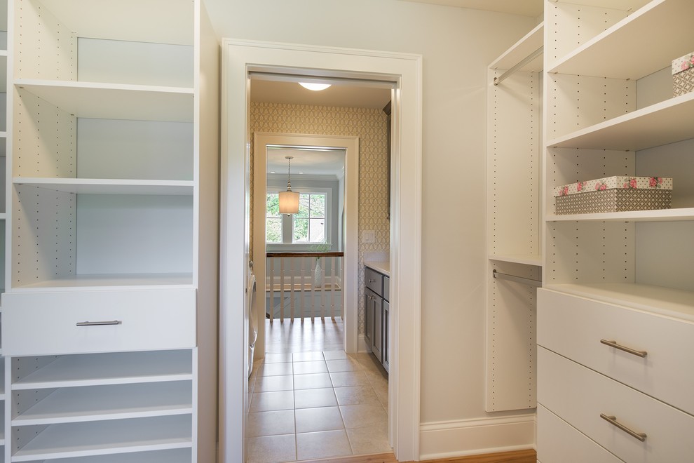 Ejemplo de armario vestidor unisex pequeño con armarios con paneles lisos, puertas de armario blancas y suelo de madera clara