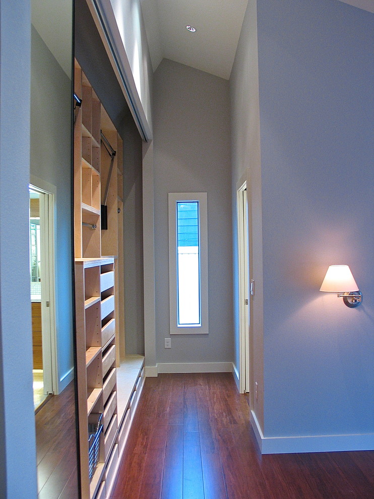 Imagen de armario unisex moderno pequeño con armarios abiertos, puertas de armario de madera clara y suelo de madera clara