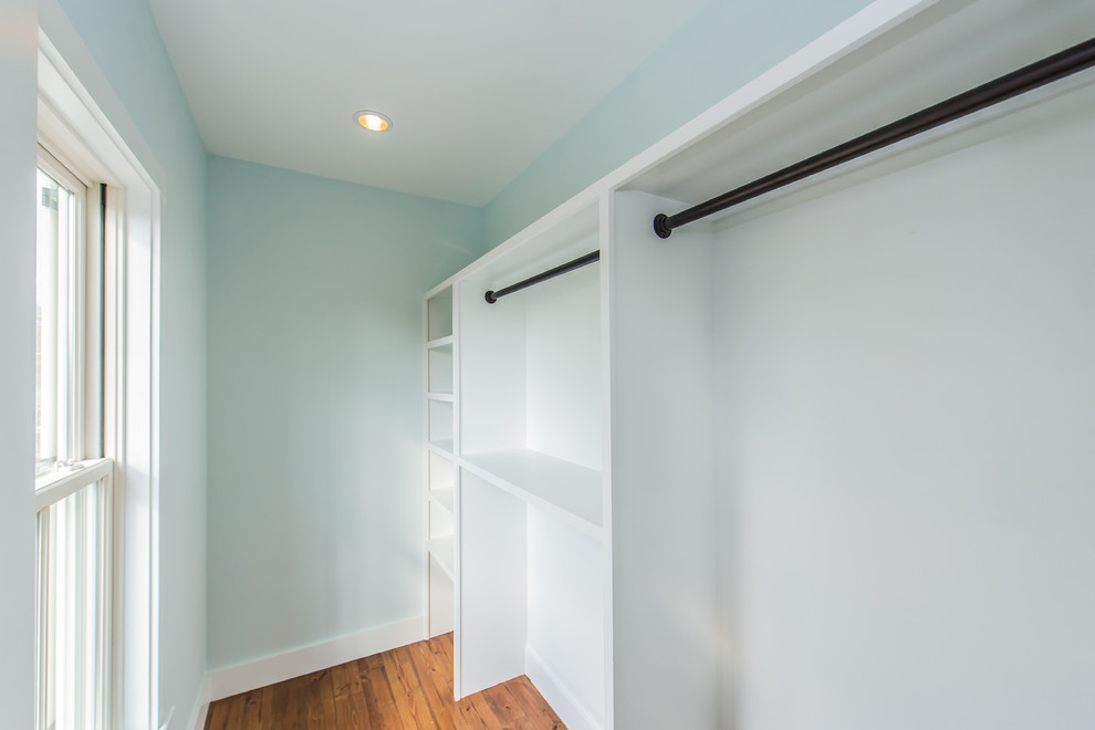 Inspiration för små klassiska walk-in-closets för könsneutrala, med vita skåp, mellanmörkt trägolv och brunt golv