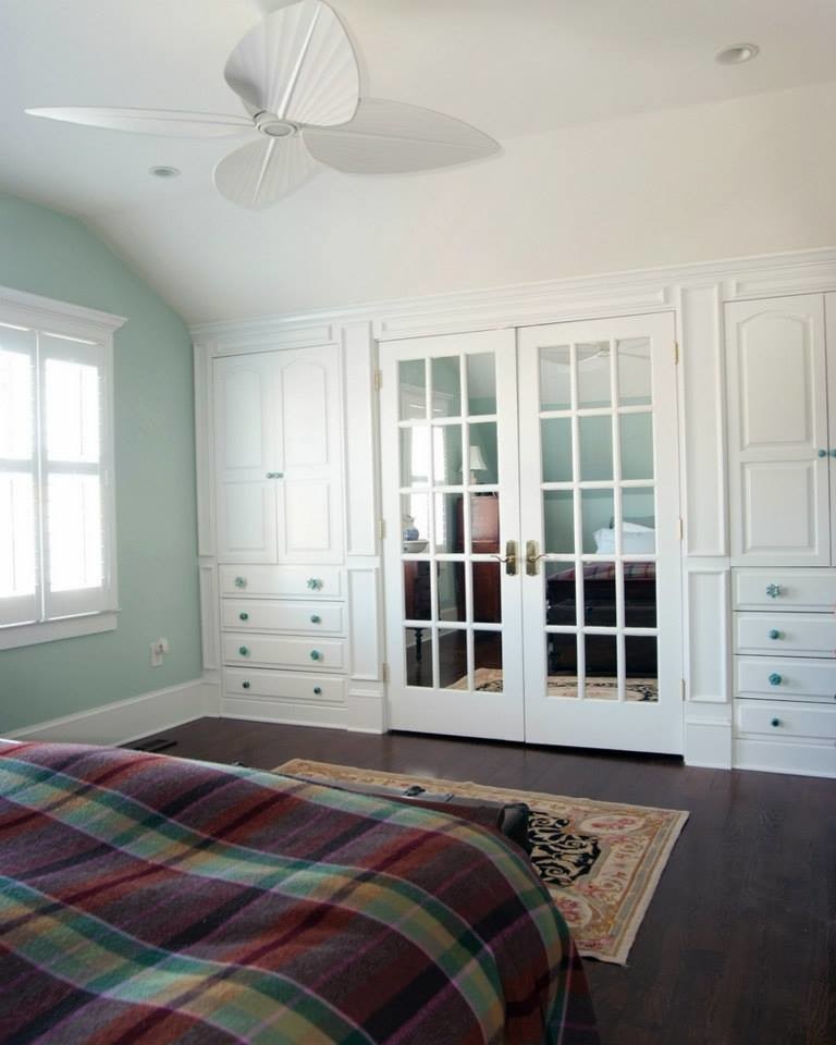 Diseño de armario unisex costero de tamaño medio con puertas de armario blancas y suelo de madera oscura