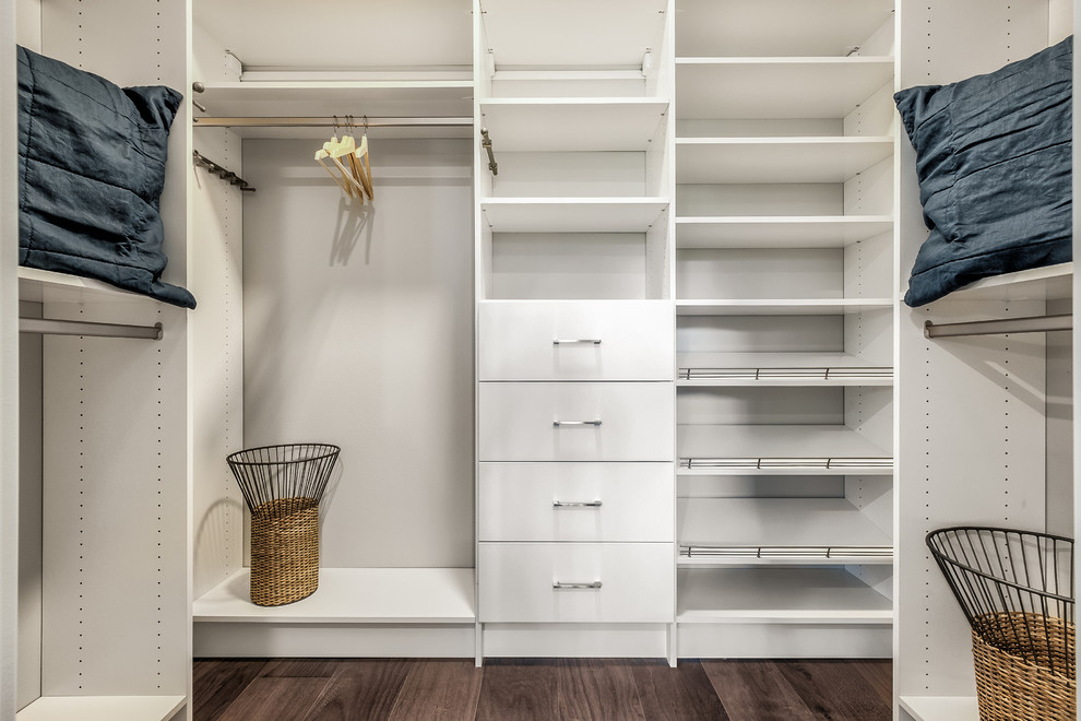 Esempio di una cabina armadio unisex minimalista con ante bianche, pavimento in legno massello medio e pavimento marrone