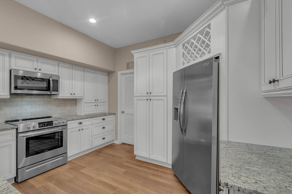 This is an example of a small traditional gender neutral standard wardrobe in Orlando with recessed-panel cabinets, light wood cabinets, laminate floors and brown floors.