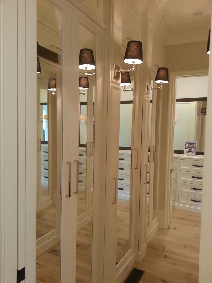 Ejemplo de armario y vestidor unisex clásico renovado con armarios con paneles empotrados, puertas de armario blancas y suelo de madera clara