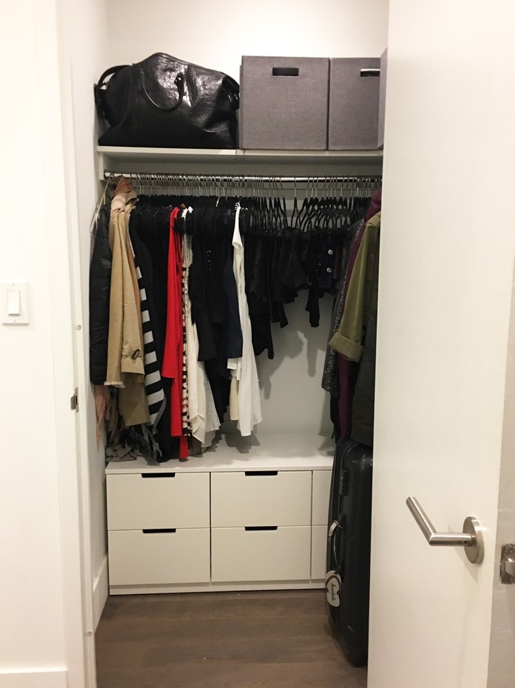 Foto de armario vestidor de mujer moderno pequeño con suelo laminado, armarios con paneles lisos, puertas de armario blancas y suelo marrón