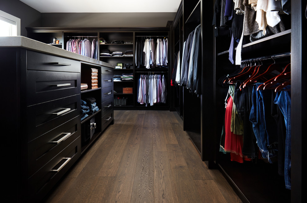 Imagen de armario vestidor unisex clásico renovado extra grande con armarios con paneles empotrados, puertas de armario negras, suelo de madera oscura y suelo marrón