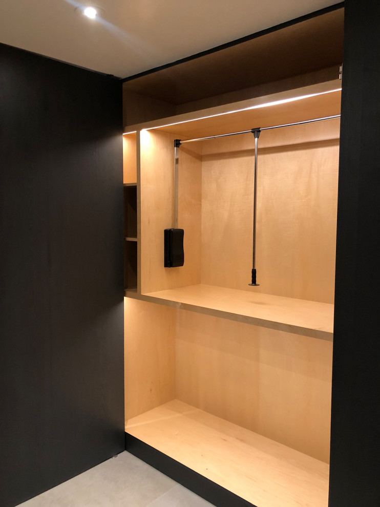 Modelo de armario vestidor unisex de tamaño medio con armarios abiertos, puertas de armario negras, suelo de cemento y suelo gris