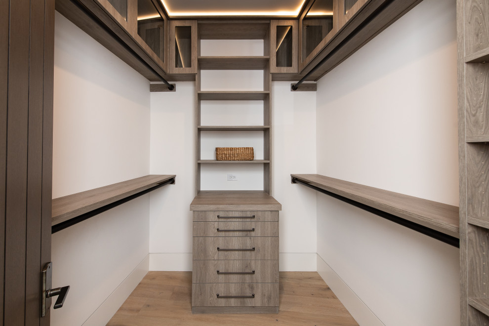 Inspiration for a large transitional gender-neutral light wood floor and beige floor walk-in closet remodel in Orange County with flat-panel cabinets and medium tone wood cabinets
