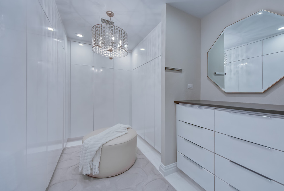 Trendy gender-neutral white floor walk-in closet photo in Tampa with flat-panel cabinets and white cabinets