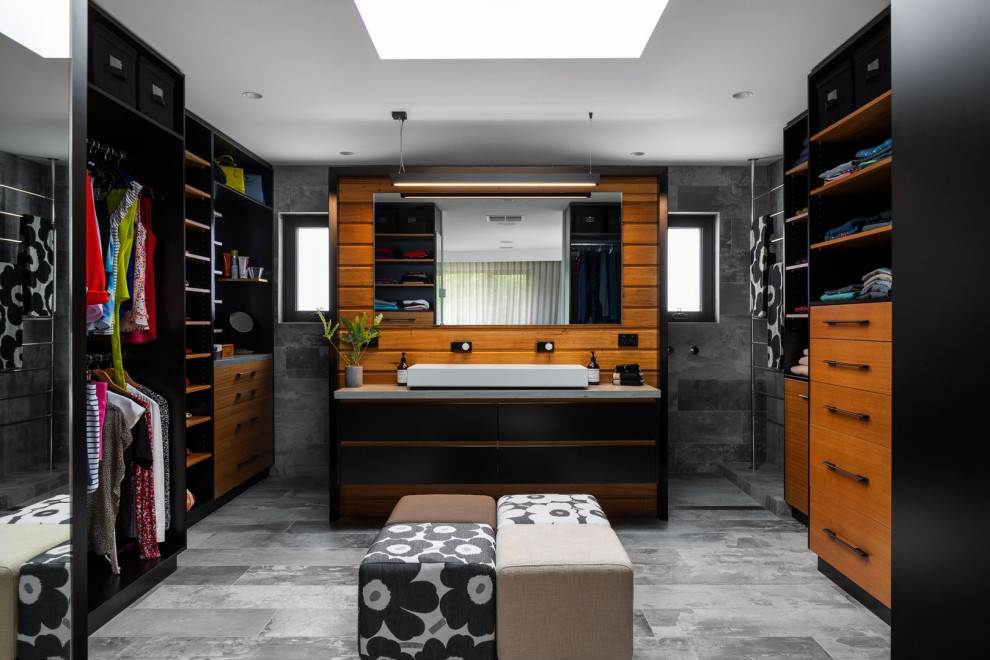 Diseño de vestidor unisex contemporáneo con puertas de armario de madera oscura y suelo gris