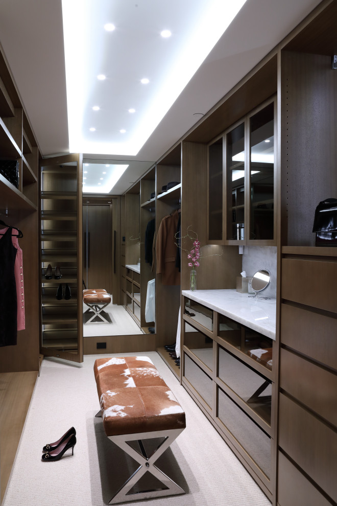 Diseño de vestidor unisex actual grande con armarios con paneles lisos, puertas de armario de madera oscura y suelo beige