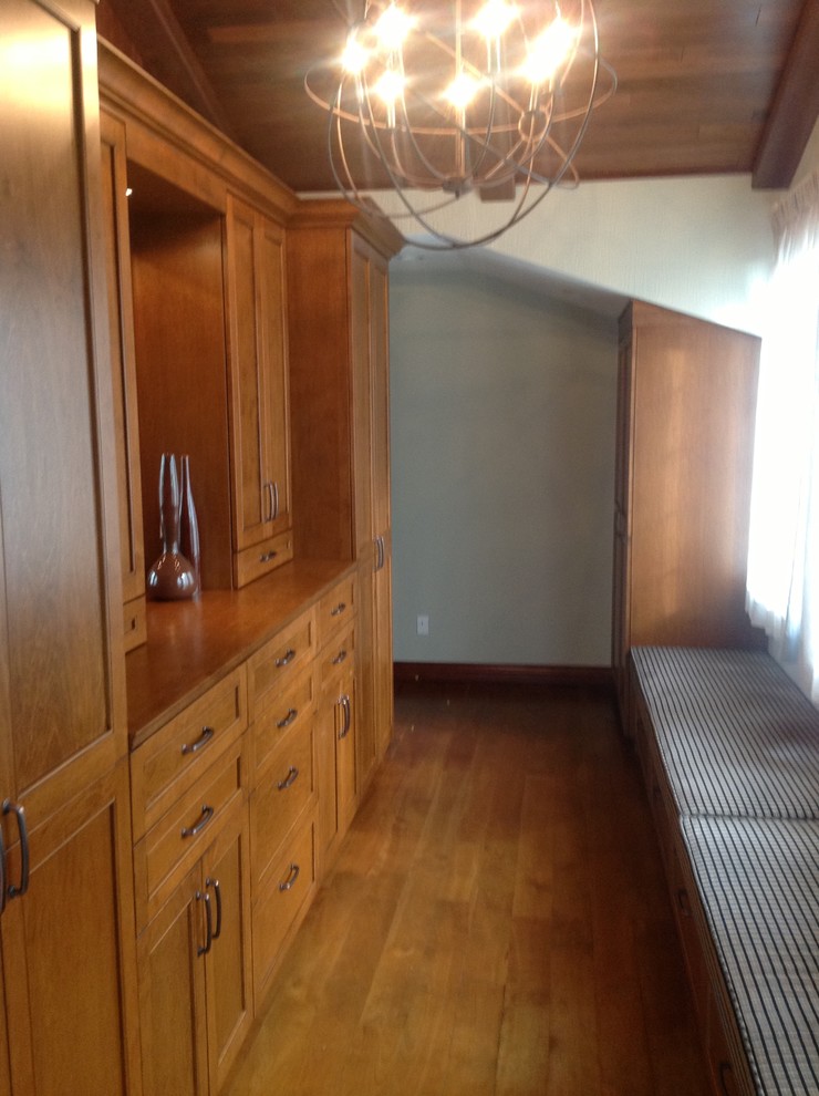 Modelo de armario vestidor unisex clásico grande con armarios estilo shaker, puertas de armario de madera oscura y suelo de madera en tonos medios