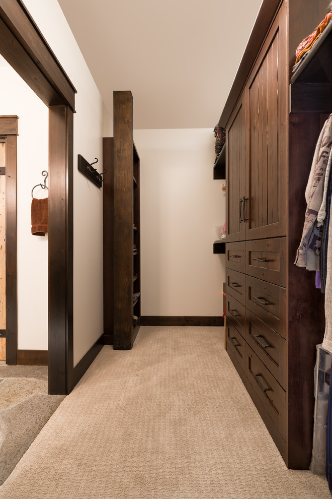 На фото: гардеробная комната в стиле рустика с фасадами с декоративным кантом, темными деревянными фасадами и ковровым покрытием