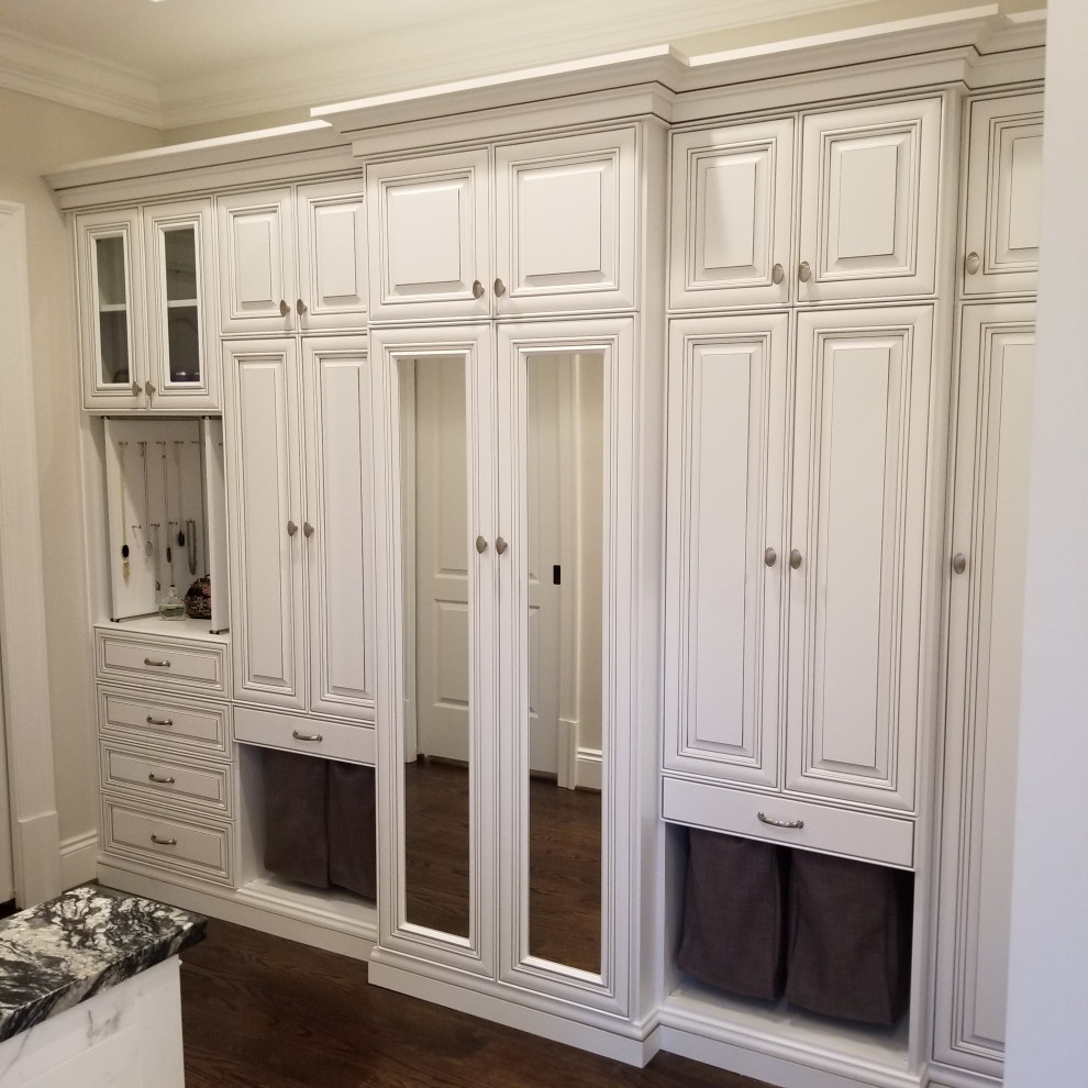 Modelo de armario y vestidor clásico pequeño con armarios con paneles con relieve, puertas de armario blancas y suelo de madera oscura