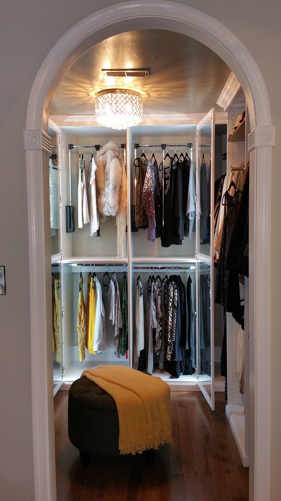 Inredning av ett klassiskt mellanstort walk-in-closet för kvinnor, med luckor med glaspanel, vita skåp och mellanmörkt trägolv