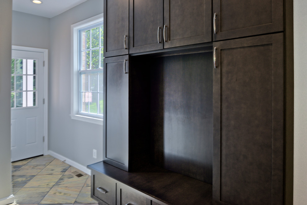 This is an example of a medium sized modern gender neutral walk-in wardrobe in DC Metro with flat-panel cabinets, black cabinets and brown floors.