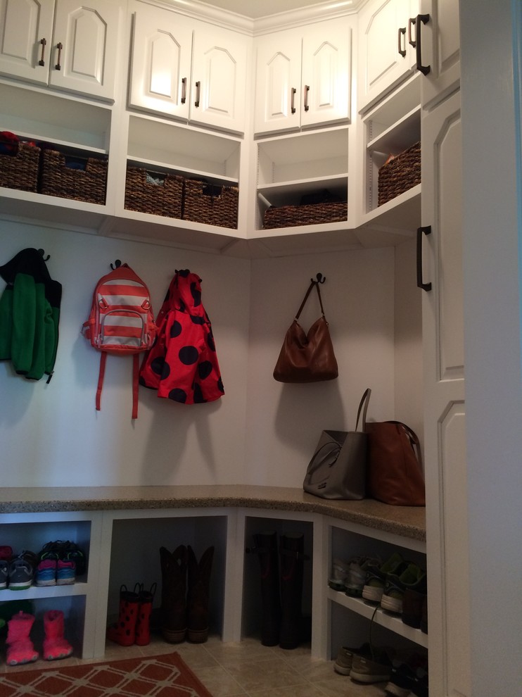Modelo de armario vestidor unisex tradicional renovado de tamaño medio con armarios con paneles con relieve, puertas de armario de madera clara y suelo de baldosas de terracota