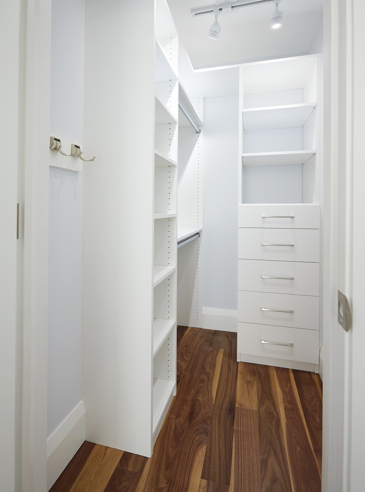 Ispirazione per una piccola cabina armadio unisex classica con ante lisce, ante bianche e pavimento in legno massello medio