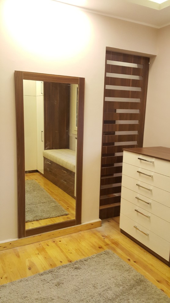 Dressing room - large modern gender-neutral laminate floor and yellow floor dressing room idea in Other with glass-front cabinets and medium tone wood cabinets