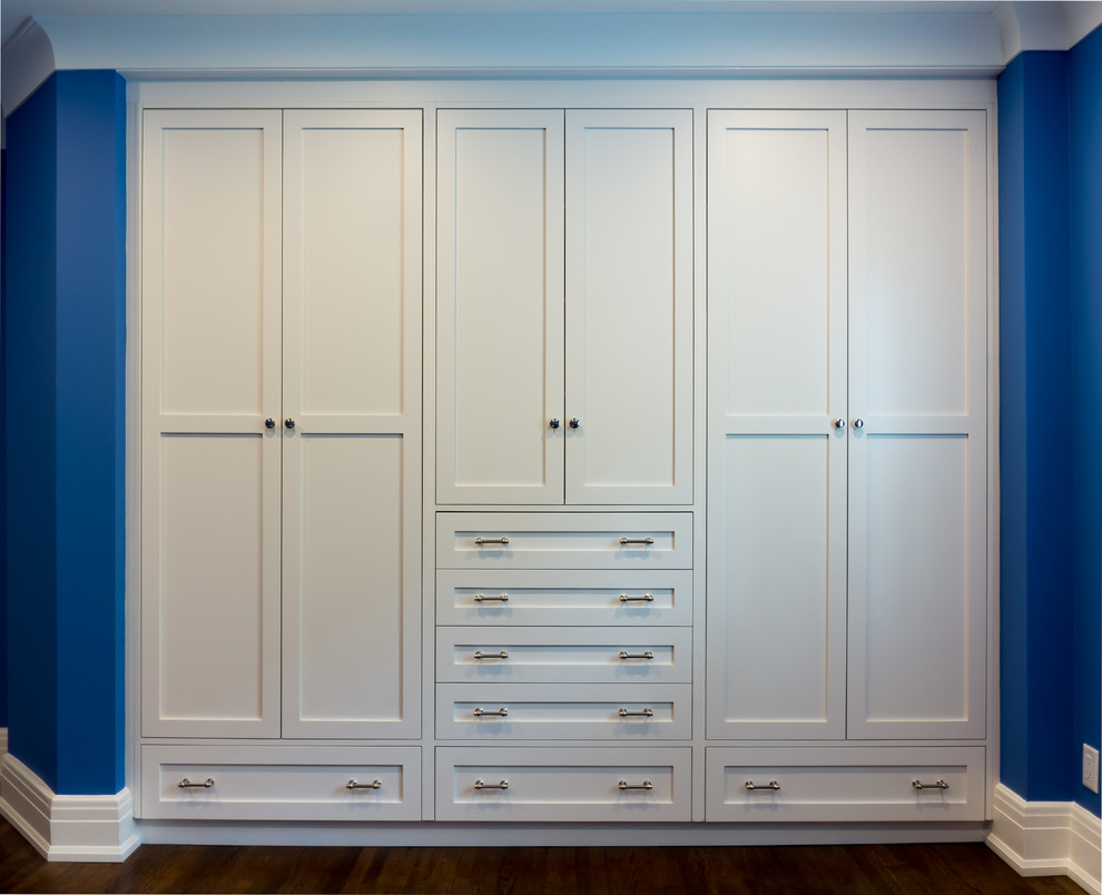 Imagen de armario unisex actual de tamaño medio con armarios estilo shaker, puertas de armario blancas, suelo de madera en tonos medios y suelo marrón