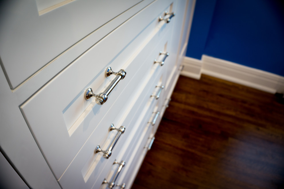 Modelo de armario unisex contemporáneo de tamaño medio con armarios estilo shaker, puertas de armario blancas, suelo de madera en tonos medios y suelo marrón
