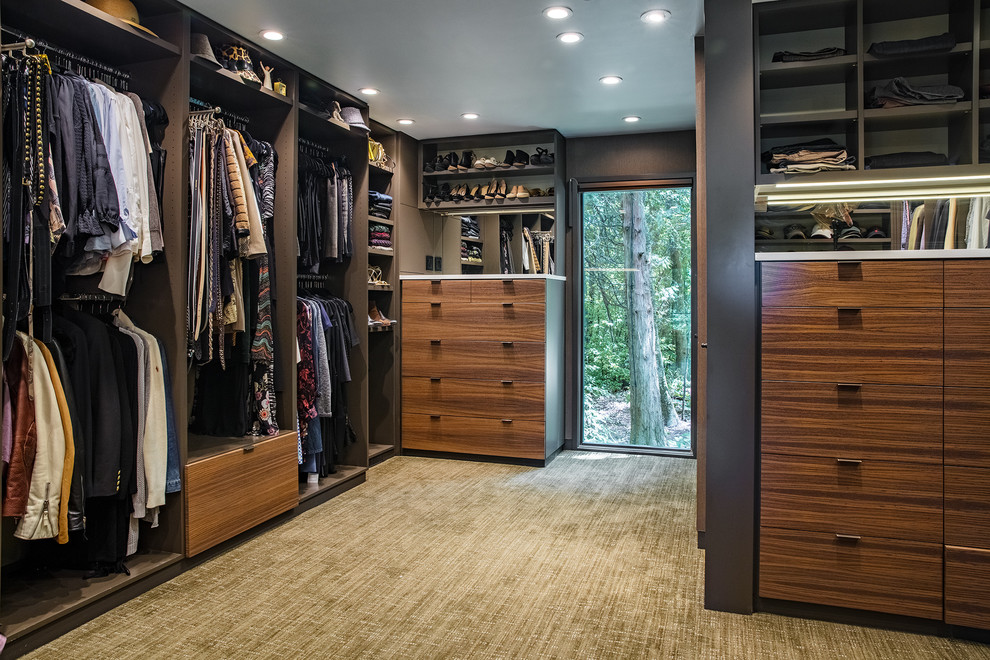 Ejemplo de armario vestidor unisex contemporáneo con armarios con paneles lisos, puertas de armario de madera en tonos medios, moqueta y suelo marrón