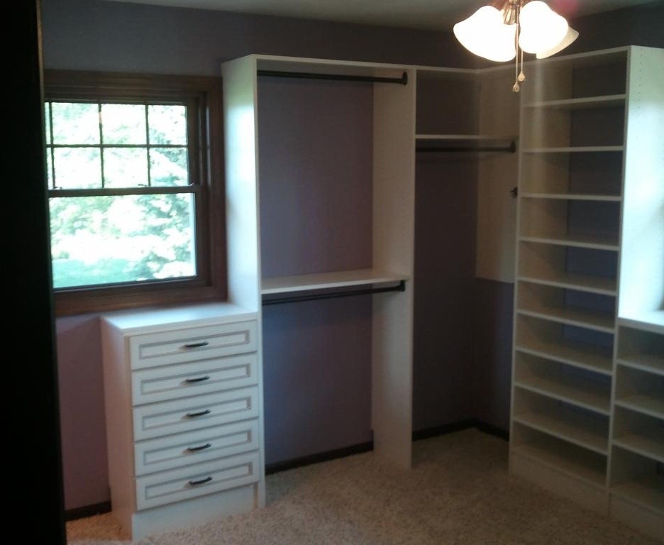 Inspiration for a mid-sized timeless gender-neutral carpeted walk-in closet remodel in Other with raised-panel cabinets and light wood cabinets