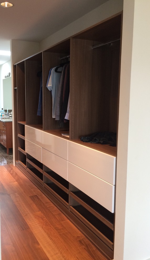 Example of a mid-sized 1950s gender-neutral walk-in closet design in Seattle with flat-panel cabinets and medium tone wood cabinets
