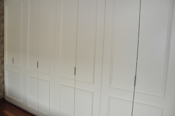 Imagen de vestidor bohemio grande con puertas de armario blancas y suelo de madera oscura