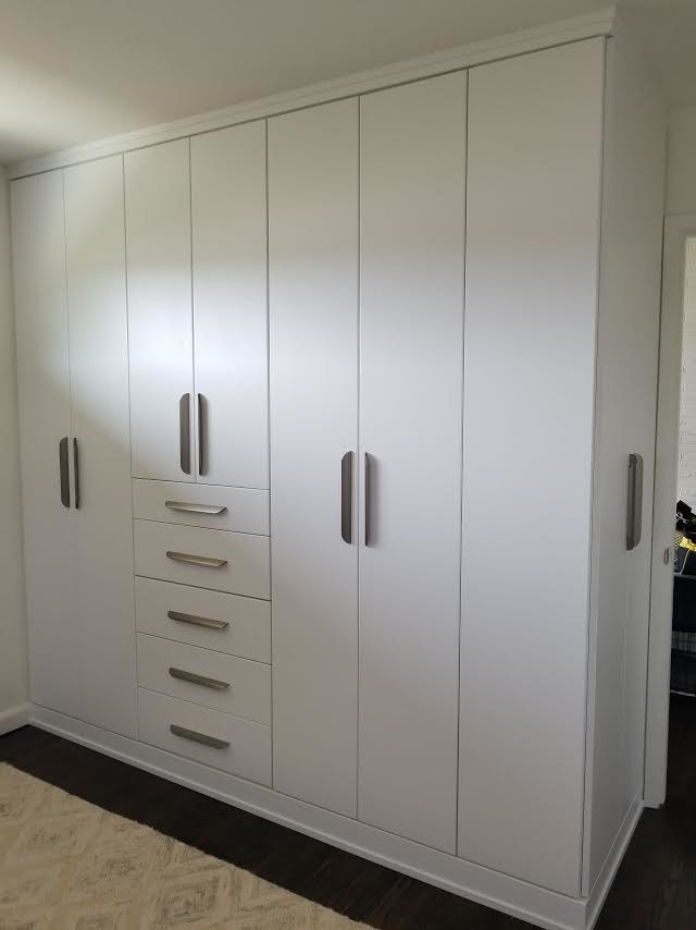 Foto de armario unisex clásico grande con armarios con paneles lisos, puertas de armario blancas, suelo de madera oscura y suelo marrón