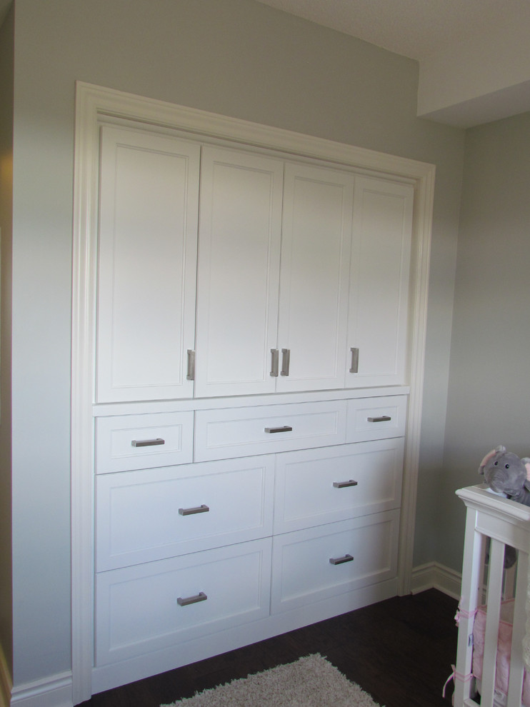 Diseño de armario de mujer actual pequeño con puertas de armario blancas, suelo de madera oscura y armarios con paneles empotrados