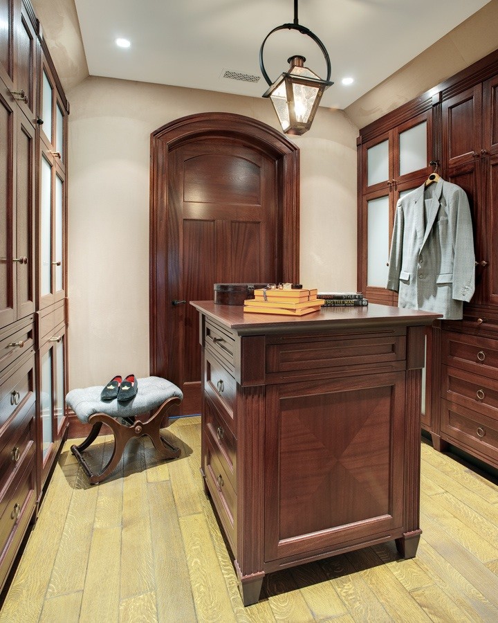 Aménagement d'un dressing room classique en bois foncé de taille moyenne pour un homme avec un placard avec porte à panneau encastré et parquet clair.