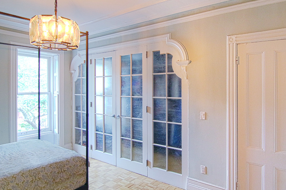 Идея дизайна: гардеробная комната среднего размера, унисекс в стиле неоклассика (современная классика) с стеклянными фасадами, белыми фасадами, светлым паркетным полом и коричневым полом