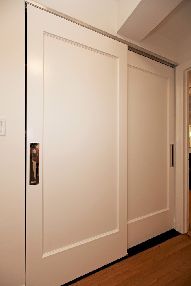Diseño de armario unisex tradicional de tamaño medio con armarios con paneles lisos, puertas de armario blancas y moqueta