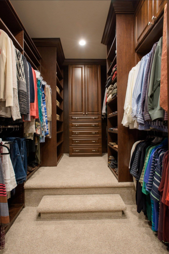 Foto de armario vestidor unisex grande con armarios con paneles con relieve, puertas de armario de madera en tonos medios, moqueta y suelo beige