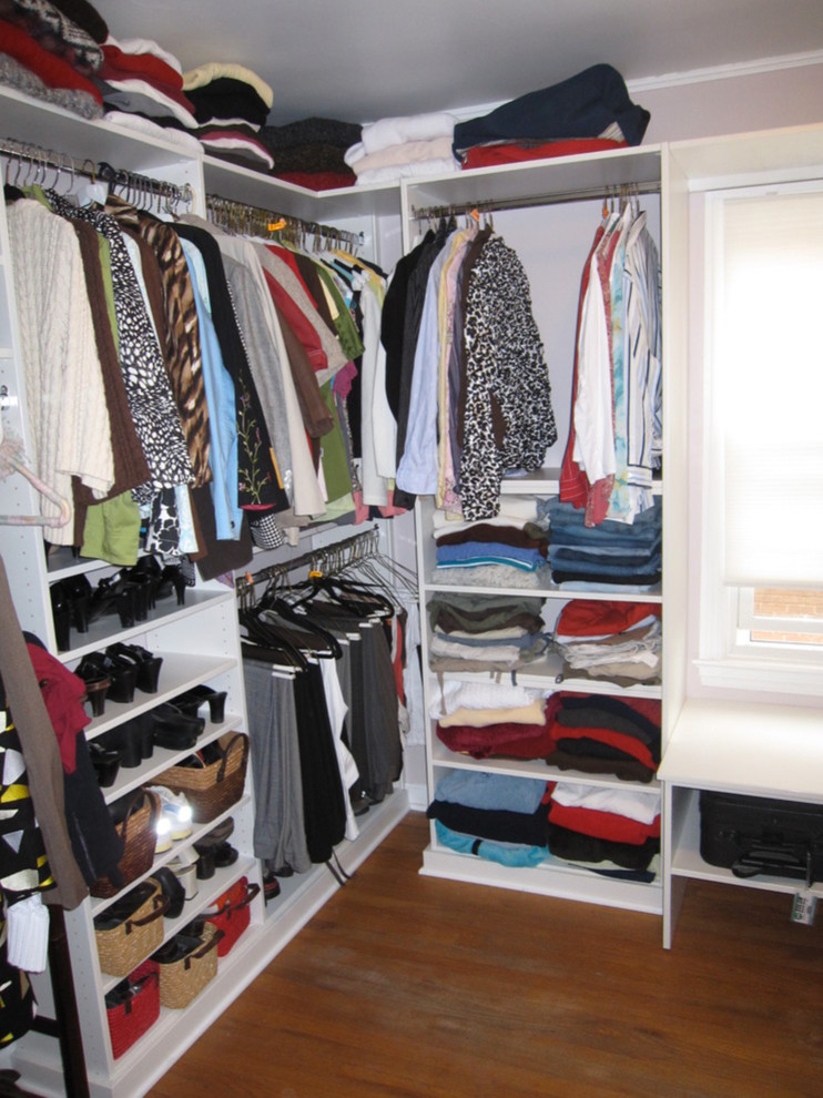 This is an example of a large gender neutral walk-in wardrobe in Cleveland with flat-panel cabinets, white cabinets, medium hardwood flooring and brown floors.