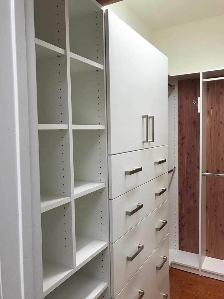Foto de armario vestidor de tamaño medio con armarios con paneles lisos, puertas de armario blancas, suelo de madera en tonos medios y suelo marrón