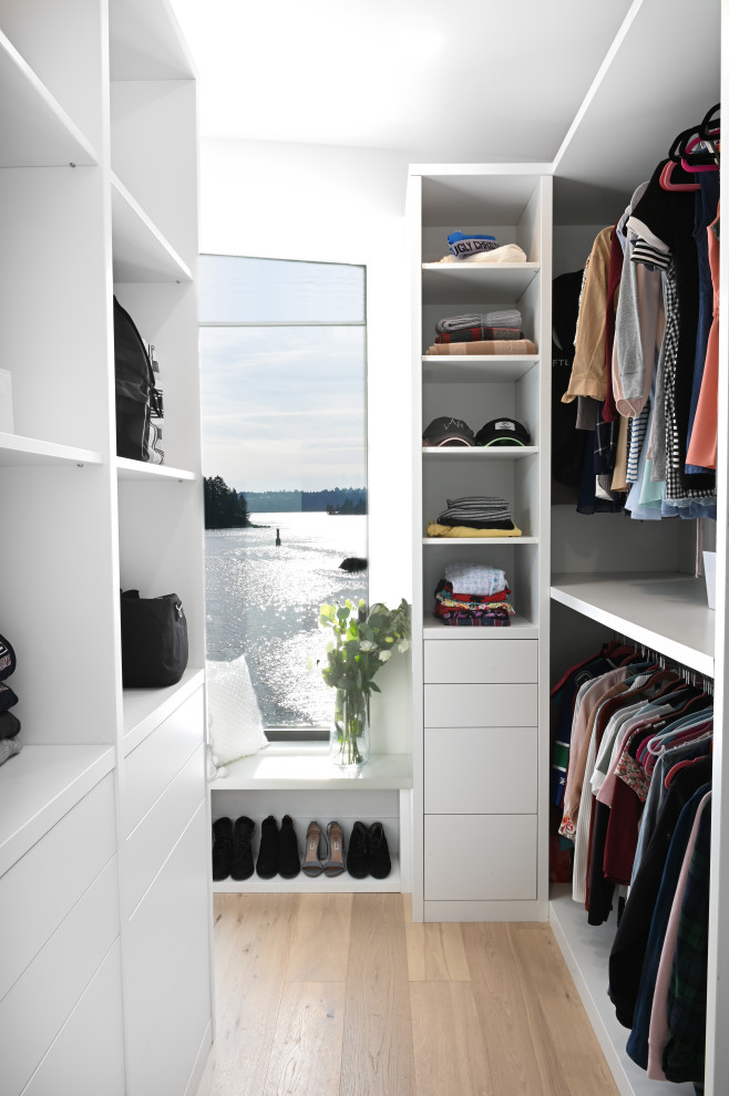 Contemporary walk-in wardrobe in Vancouver with open cabinets, white cabinets and light hardwood flooring.