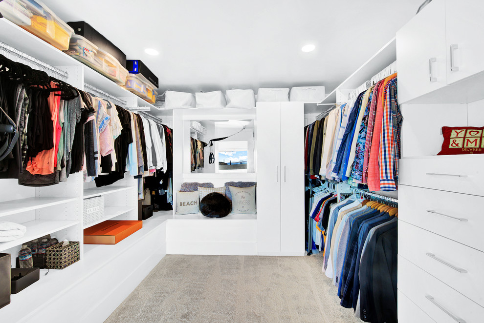 This is an example of a medium sized contemporary gender neutral walk-in wardrobe in San Francisco with flat-panel cabinets, white cabinets, carpet and beige floors.