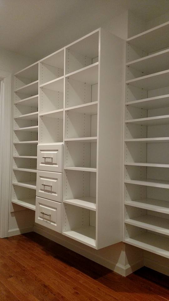 Imagen de armario vestidor unisex minimalista grande con armarios con paneles con relieve, puertas de armario blancas y suelo de madera en tonos medios
