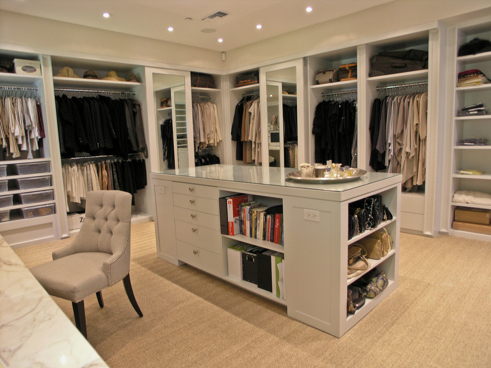 Medium sized contemporary gender neutral dressing room in Los Angeles with open cabinets, beige cabinets and carpet.
