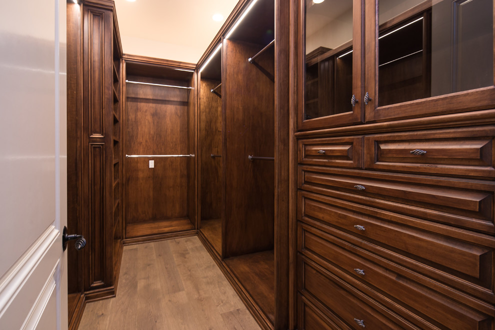 Идея дизайна: гардеробная комната в средиземноморском стиле с темными деревянными фасадами, паркетным полом среднего тона и коричневым полом для мужчин