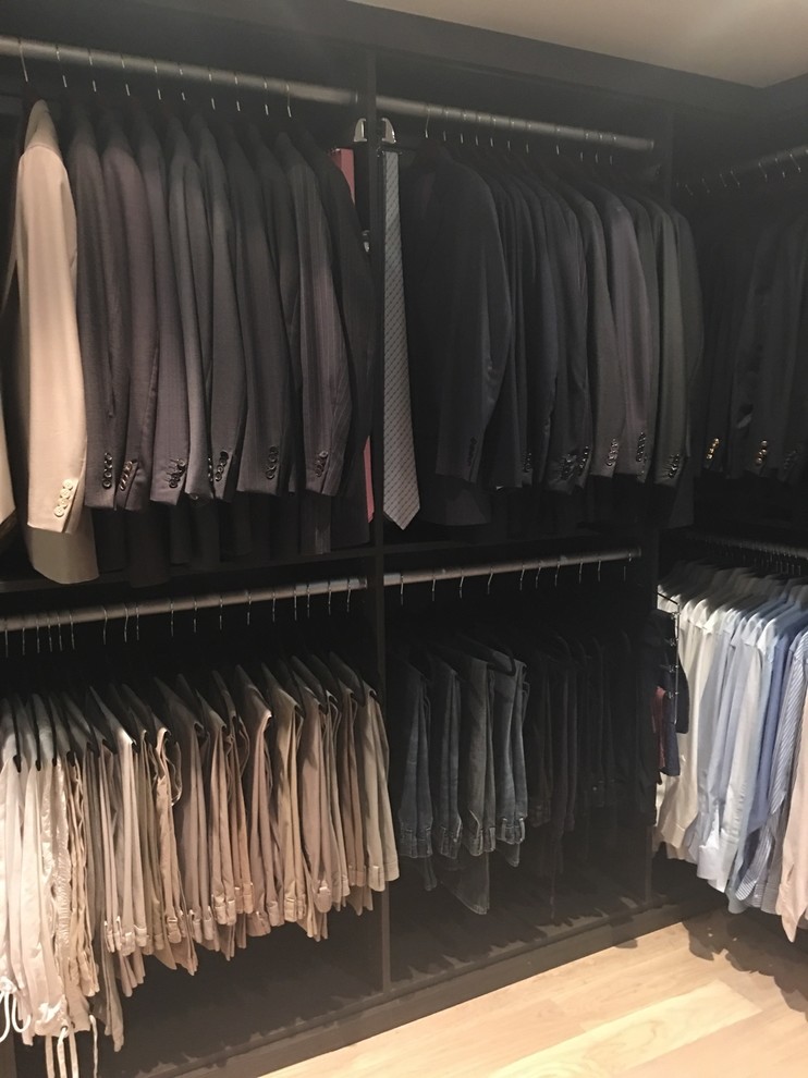 Ejemplo de armario vestidor unisex actual de tamaño medio con armarios con paneles lisos, puertas de armario grises y suelo de madera clara