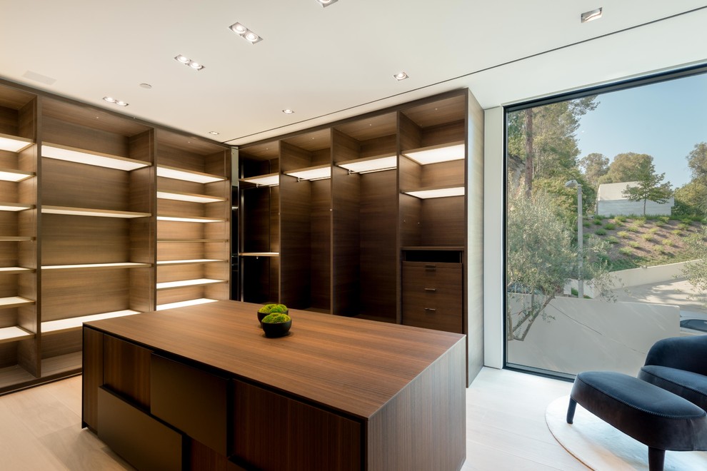 This is an example of an expansive modern gender neutral walk-in wardrobe in Los Angeles with open cabinets, dark wood cabinets, laminate floors and beige floors.