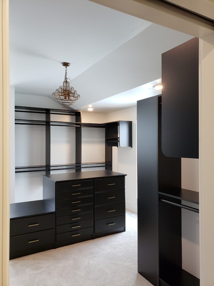 Ejemplo de armario vestidor unisex tradicional renovado con armarios con paneles lisos, puertas de armario negras, moqueta y suelo beige