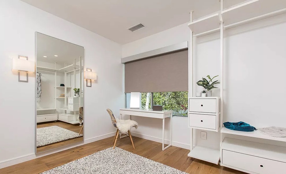 Geräumiger Moderner Begehbarer Kleiderschrank mit flächenbündigen Schrankfronten, weißen Schränken, braunem Holzboden und braunem Boden in Los Angeles