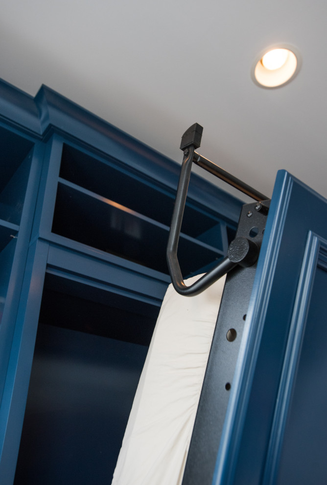 На фото: встроенный шкаф среднего размера, унисекс в стиле неоклассика (современная классика) с фасадами с утопленной филенкой, синими фасадами, полом из ламината и коричневым полом