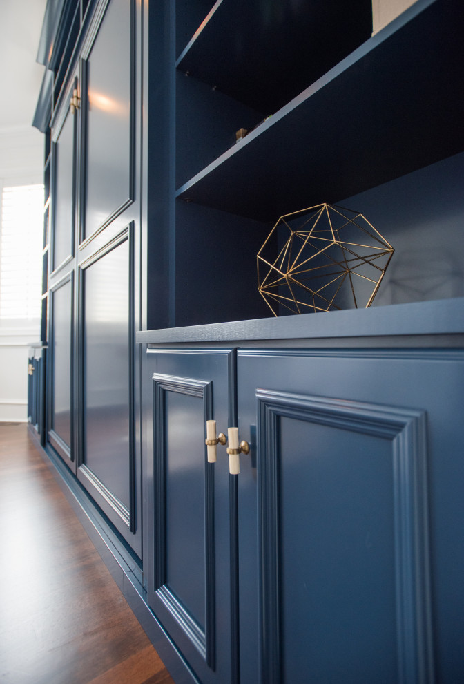 Inspiration for a medium sized traditional gender neutral built-in wardrobe in Denver with recessed-panel cabinets, blue cabinets, laminate floors, brown floors and a vaulted ceiling.