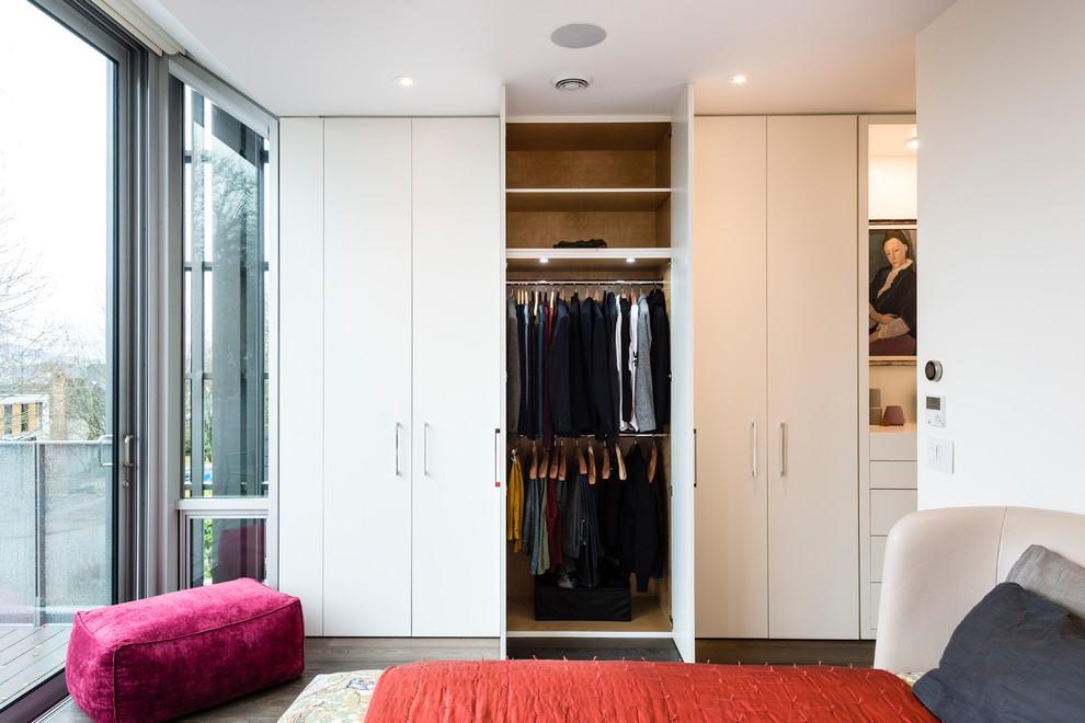 Ejemplo de armario contemporáneo de tamaño medio con armarios con paneles lisos, puertas de armario blancas, suelo de madera oscura y suelo marrón
